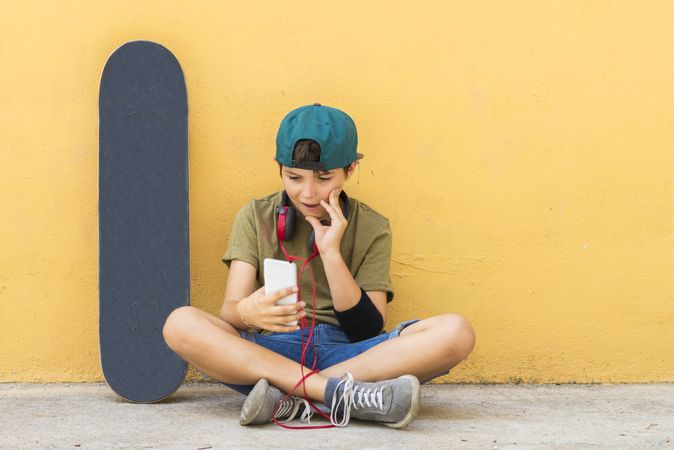 Portrait of a teenager sitting on the floor on a street checking messages