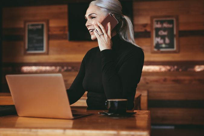 Businesswoman sitting at cafe having conversation on phone with client