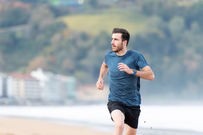 Sportsman in active wear jogging on lonely beach