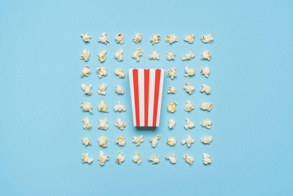 Popcorn flakes and striped box flat lay on a blue background