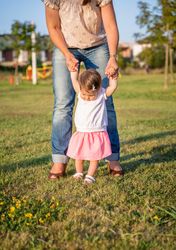Baby girl learning to walk over a grass park