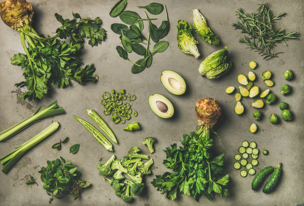 Arrangement of fresh green sliced garden vegetables on concrete surface