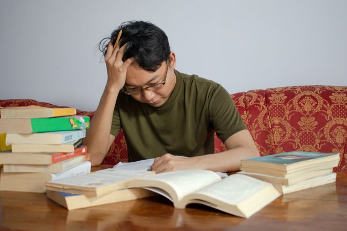 Asian young male reading book with frustrated gesture