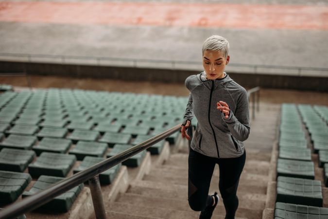 Female athlete running up the stairs of a stadium