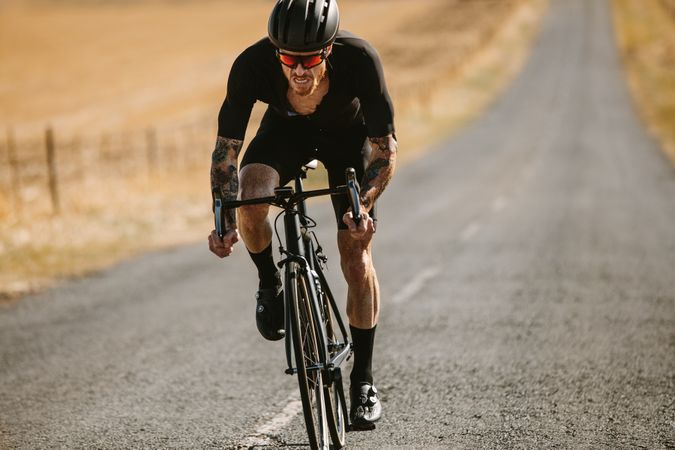 Fit man cycling outdoors on long road