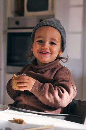 Cute little boy eating pancake in kitchen
