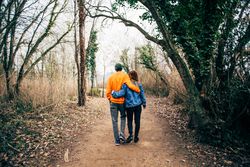 Back of loving couple walking through a forest