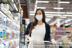 Woman in surgical mask pushing grocery cart 0JOV85