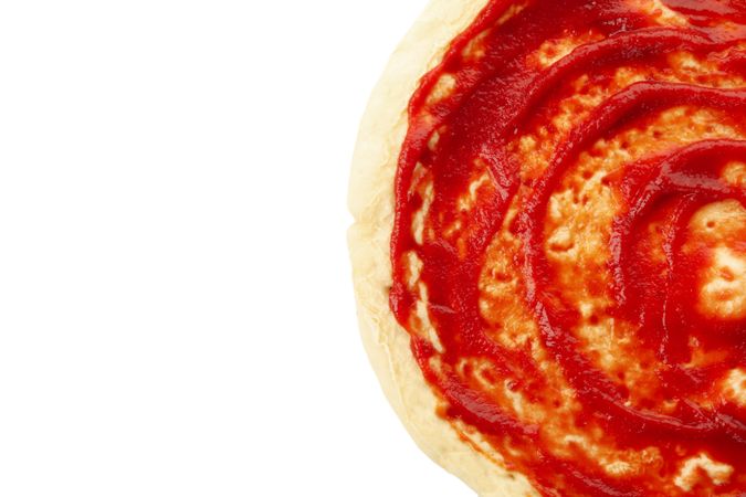 Rolled out pizza dough with sauce isolated on white background
