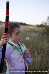 Little girl holding a dandelion puff standing outside in the evening 432wR5