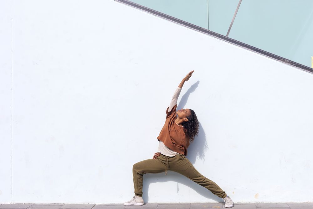Female in sportswear stretching before running against wall