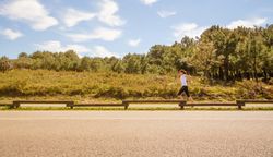 Side view of woman in athletic gear jogging along road