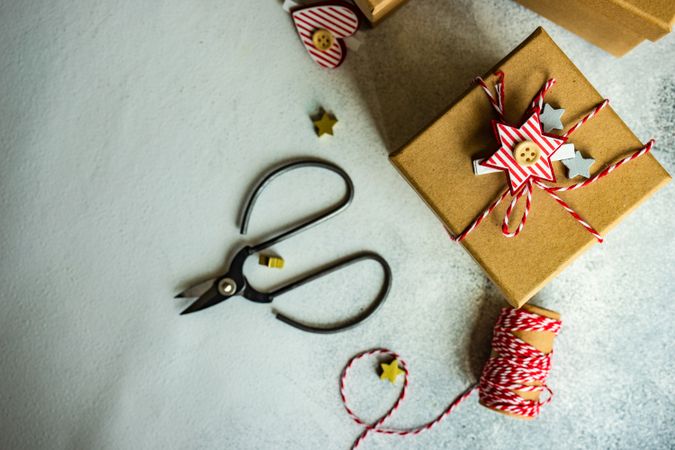 Top view of brown Christmas present with star decorations, scissors and string