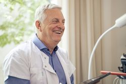 Portrait of a happy grey hair doctor smiling in his office.
