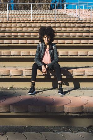 Woman with afro hair sitting on the steps of a stadium