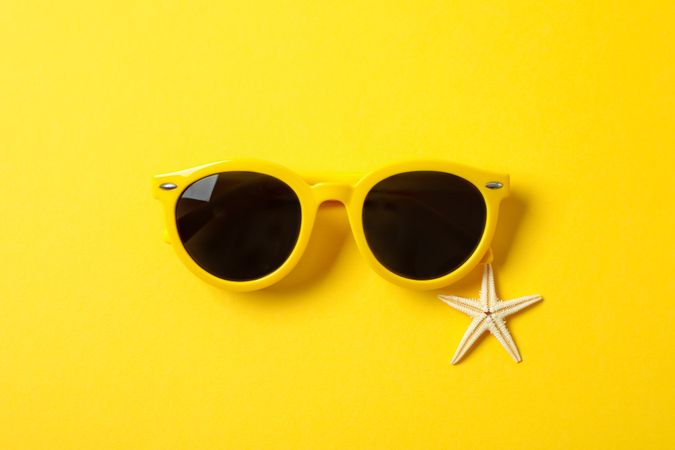 Sunglasses and starfish on color background, space for text and closeup. Summer vacation backdrop