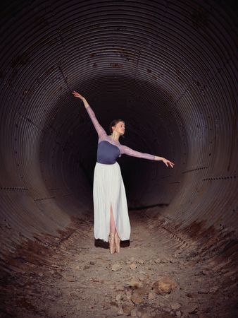 Graceful woman dancing ballet in shabby tunnel