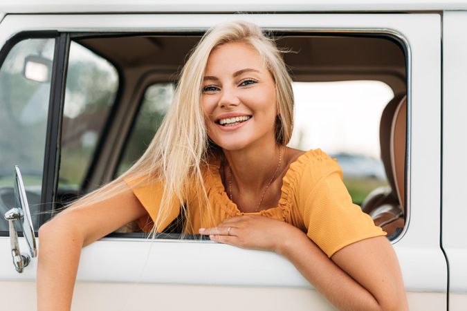 Woman smiling leaning out of driver’s seat in vehicle