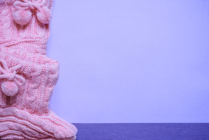 Knitted pink booties on purple background