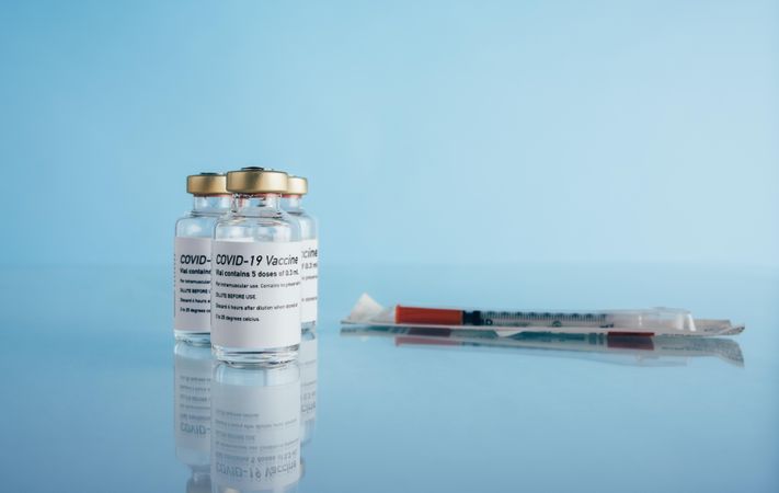 Corona virus immunity vaccine vials and syringe on blue background
