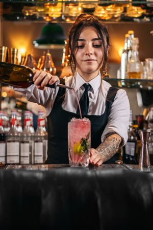 Female bartender preparing a cocktail in a traditional cocktail bar