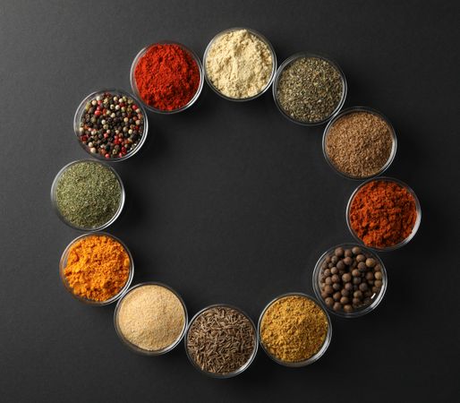 Circle of bowls of spices on dark table