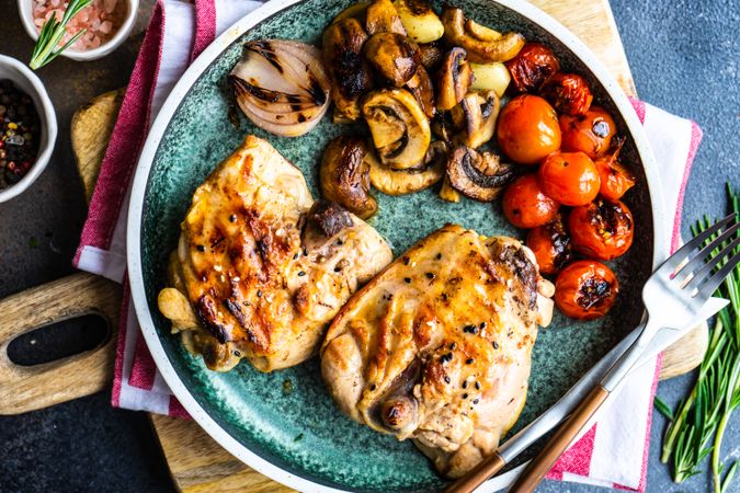 Top view of plate of grilled chicken with tomatoes and mushroom