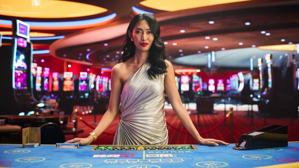 Portrait of a Professional Asian Croupier in a Casino Dealing Playing Cards on a Baccarat Table.