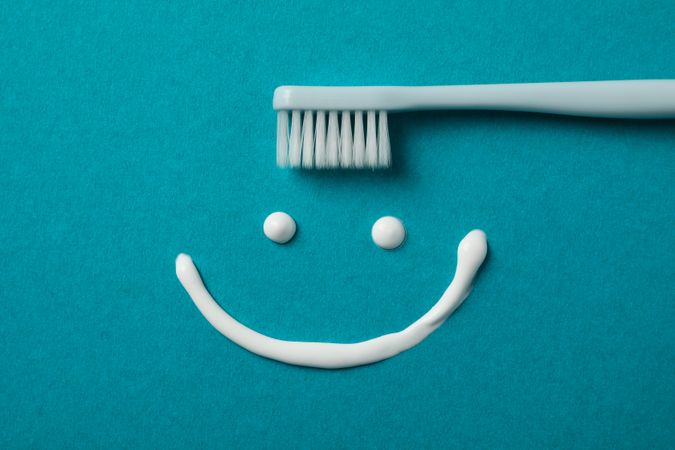 Smile made of toothpaste on turquoise background, top view