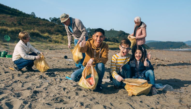 Young man and children cleaning the beach