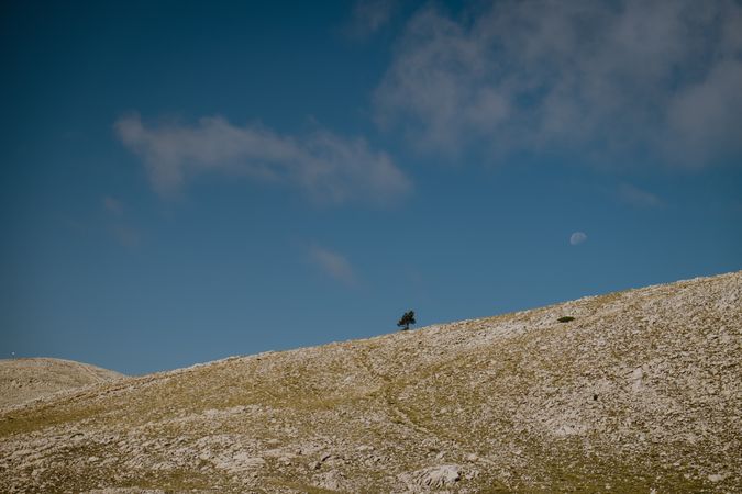 Landscape with hill and moon in blue sky