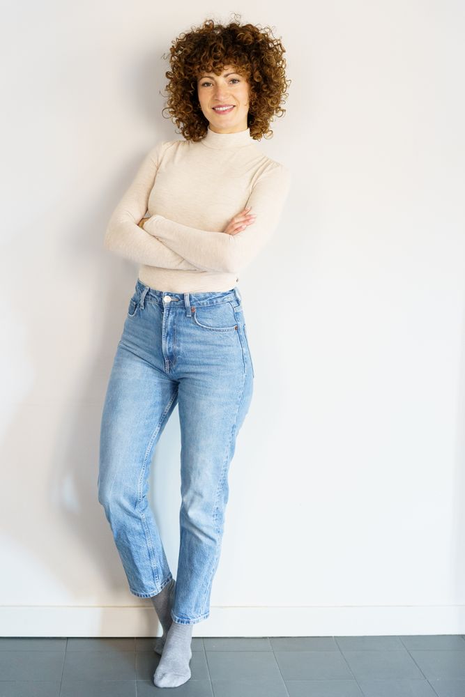 Smiling woman in casual clothes with arms crossed, vertical