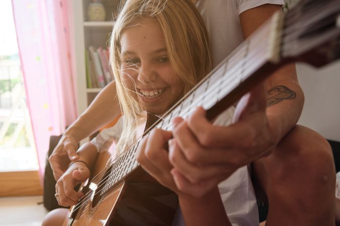 Smiling girl and a woman playing guitar in a house