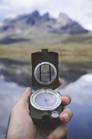 Crop hand with compass near lake