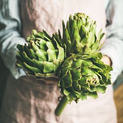 Close up of woman holding fresh artichokes