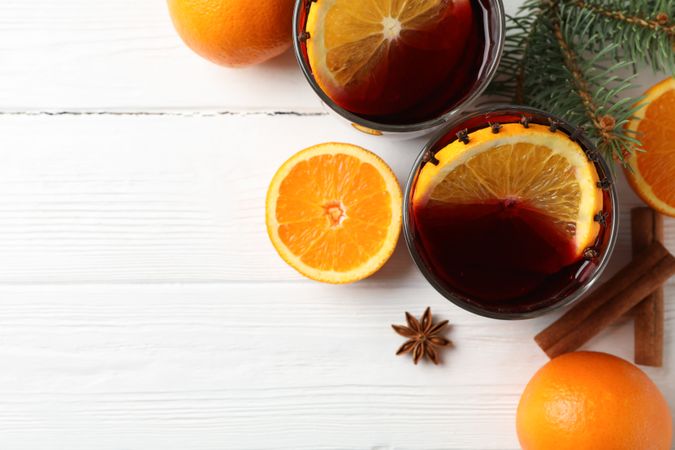 Glasses of tasty mulled wine with orange on wooden background, space for text