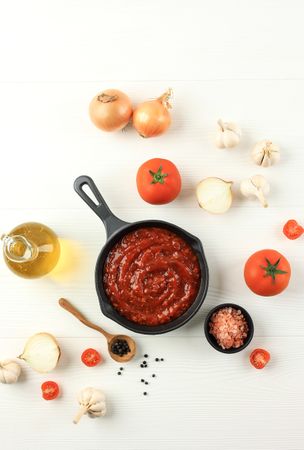 Top view of Italian tomato sauce with garlic bulbs, onions and tomatoes on table