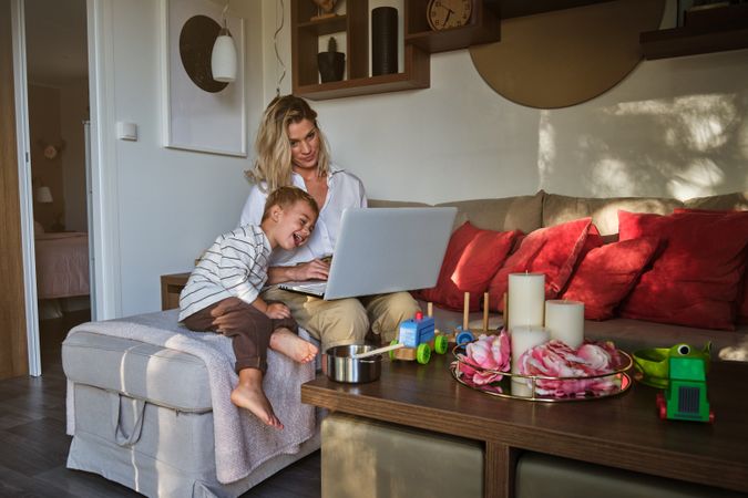 Mother and son watching funny video on laptop in living room