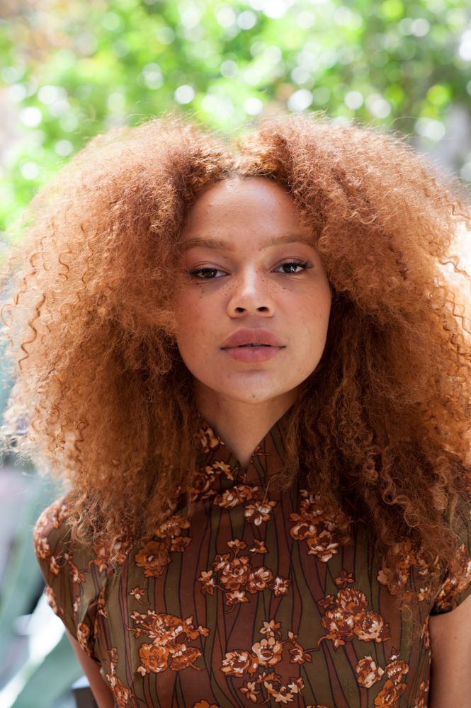 Close up portrait of a young woman with an afro facing the camera