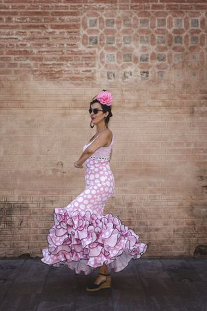 Passionate woman in flamenco dress dancing on street
