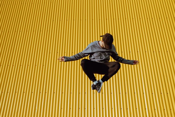 Man jumping near yellow wall