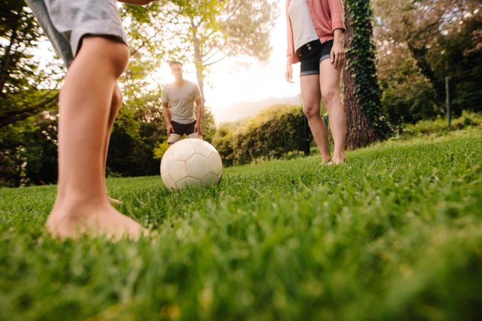 Football on grass with family standing around outdoors in park