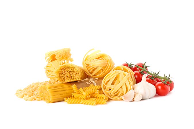 Pasta and vegetables isolated on light background. Uncooked whole wheat pasta