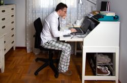 Man teleworking wearing shirt, tie and pajama pants