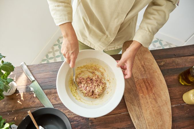 Anonymous cook preparing steak tartare in kitchen