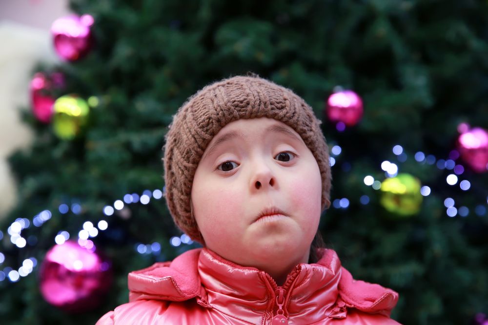 Young girl expressing sadness standing against a decorated tree