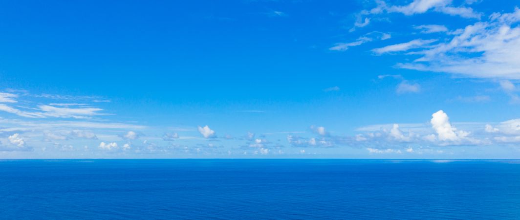 Clear blue Indian Ocean under a blue sky with clouds, wide