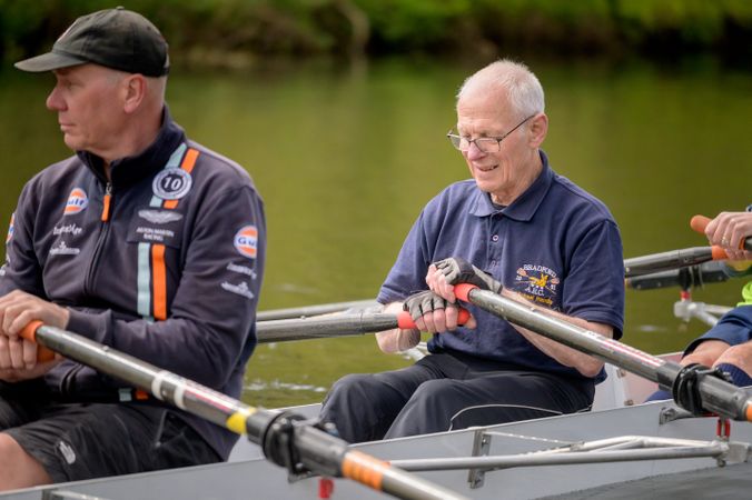Happy older men rowing in river