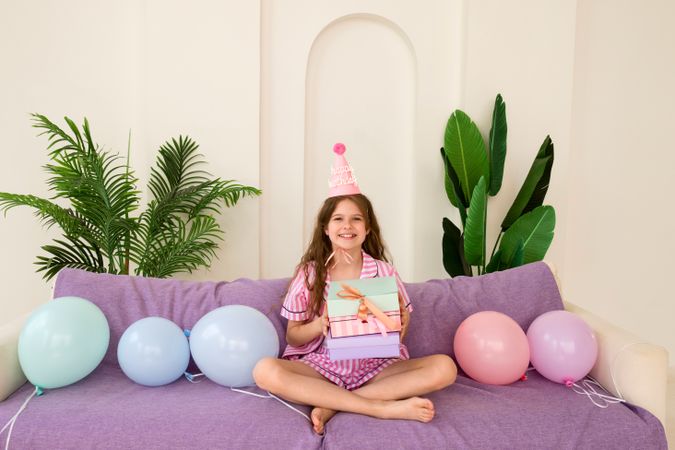 Young girl celebrating birthday at home with gifts and balloons.