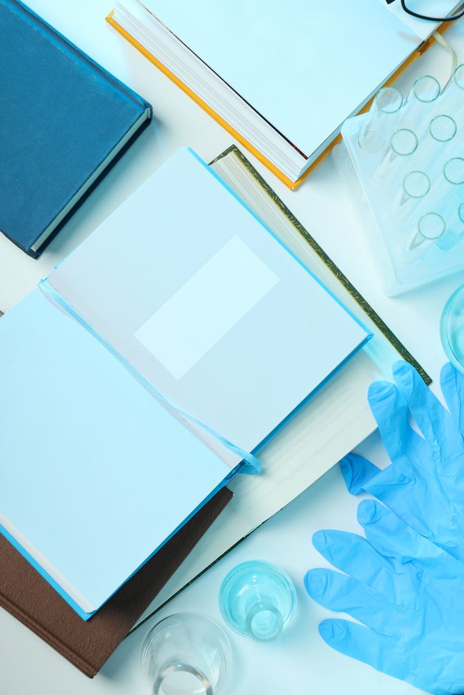 Books, flasks and gloves on light background, top view